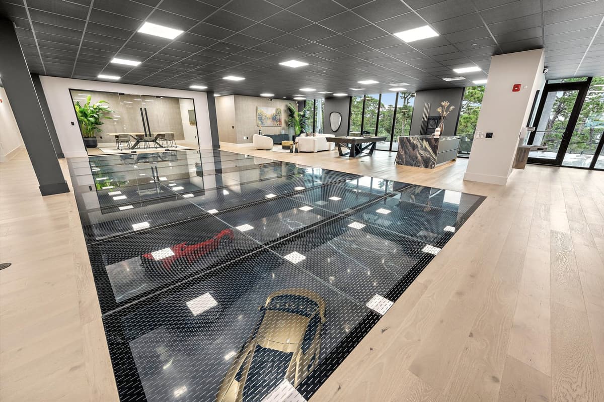 Upper floor with a glass panel set into the floor over the car gallery below, a lounge beyond